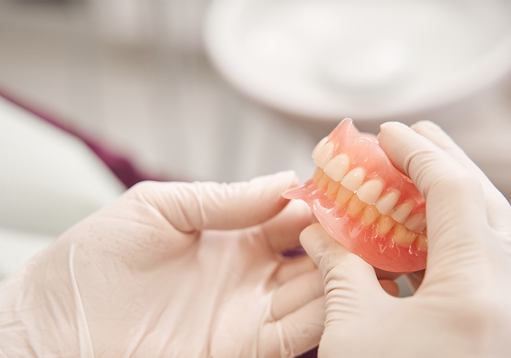 holding-dentures while wearing white gloves