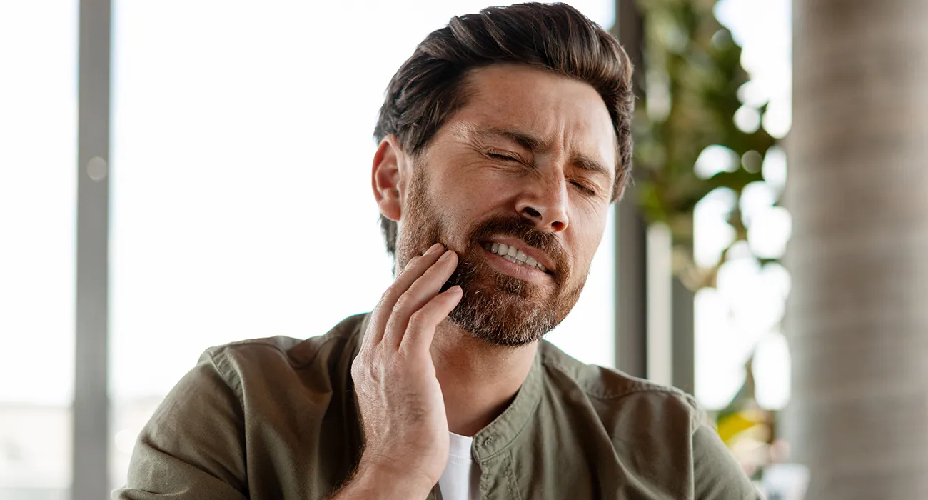 man holding mouth in pain