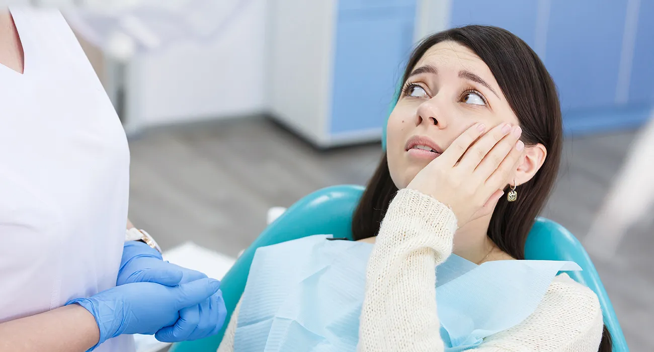 Woman holding her mouth due to tooth pain