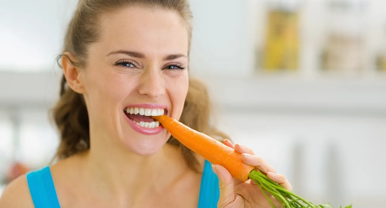 woman chewing on carrot